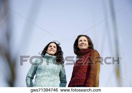 Low angle view of two mature women standing together and smiling View Large Photo Image Stock Photograph - Low angle view of two mature women standing together and smiling. Fotosearch