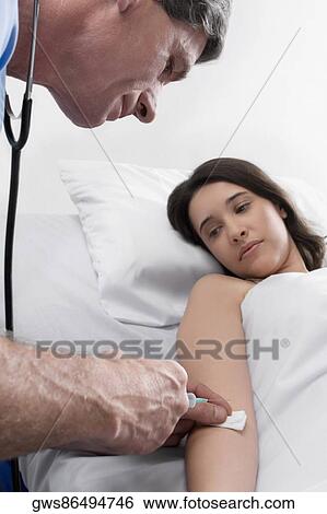 Male doctor giving an injection to a female patient View Large Photo Image Stock Photograph - Male doctor giving an injection to a female patient. Fotosearch