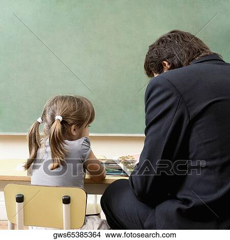 Picture - Male teacher teaching his student in a classroom. Fotosearch