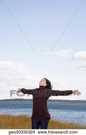 Mature woman standing on the beach with her arms outstretched View Large Photo Image Picture - Mature woman standing on the beach with her arms outstretched. Fotosearch