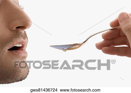 Mid adult man holding a spoon and taking medicine View Large Photo Image Picture - Mid adult man holding a spoon and taking medicine. Fotosearch