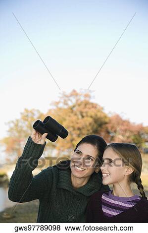Stock Photo - Mid adult woman with her daughter looking through binoculars. Fotosearch