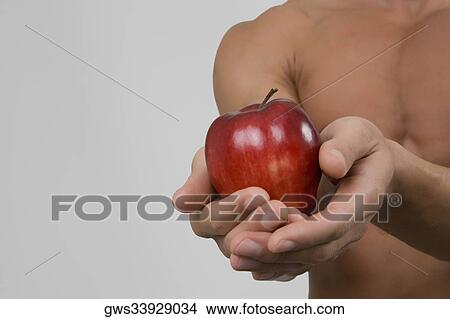 Mid section view of a man holding an apple View Large Photo Image Picture - Mid section view of a man holding an apple. Fotosearch