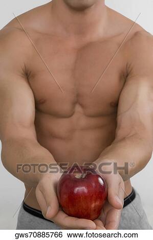 Stock Photograph - Mid section view of a man holding an apple. Fotosearch