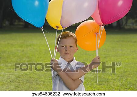 Portrait of a boy holding balloons in a park View Large Photo Image Stock Image - Portrait of a boy holding balloons in a park. Fotosearch