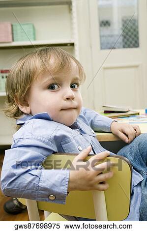 Portrait of a boy sitting on a chair View Large Photo Image Stock Photography - Portrait of a boy sitting on a chair. Fotosearch