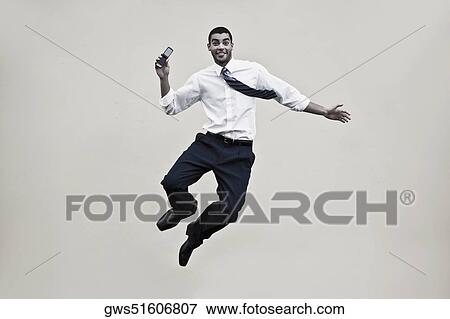 Portrait of a businessman holding a mobile phone and jumping View Large Photo Image Stock Photo - Portrait of a businessman holding a mobile phone and jumping. Fotosearch
