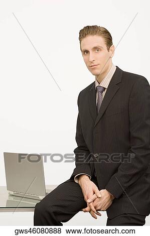Portrait of a businessman sitting on a desk View Large Photo Image Stock Photo - Portrait of a businessman sitting on a desk. Fotosearch