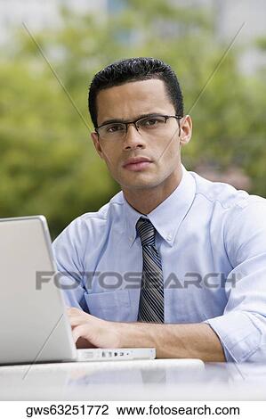Portrait of a businessman using a laptop at a sidewalk cafe View Large Photo Image Stock Image - Portrait of a businessman using a laptop at a sidewalk cafe. Fotosearch