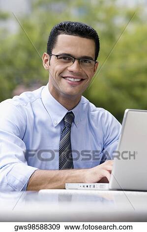 Portrait of a businessman using a laptop at a sidewalk cafe View Large Photo Image Stock Photo - Portrait of a businessman using a laptop at a sidewalk cafe. Fotosearch