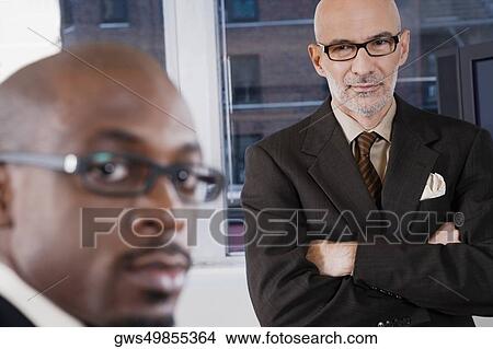 Portrait of a businessman with another businessman standing behind him View Large Photo Image Picture - Portrait of a businessman with another businessman standing behind him. Fotosearch