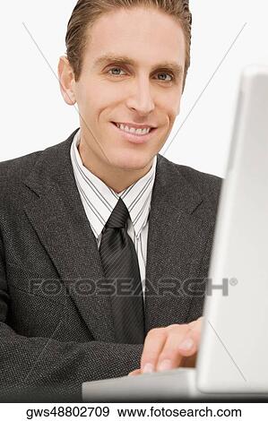 Portrait of a businessman working on a laptop and smiling View Large Photo Image Stock Photo - Portrait of a businessman working on a laptop and smiling. Fotosearch