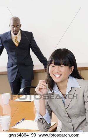 Portrait of a businesswoman smiling with other businessman standing in the background View Large Photo Image Stock Image - Portrait of a businesswoman smiling with other businessman standing in the background. Fotosearch