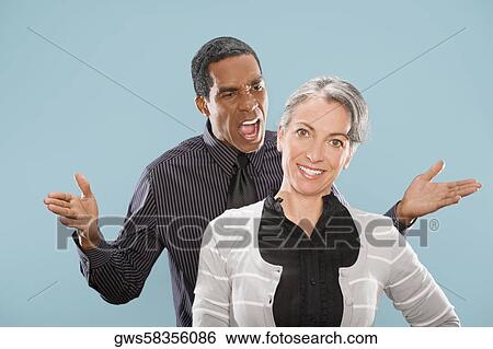 Portrait of a businesswoman smiling with a businessman shouting at her View Large Photo Image Stock Photograph - Portrait of a businesswoman smiling with a businessman shouting at her. Fotosearch