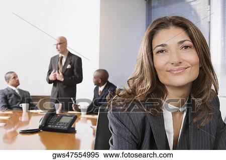 Stock Photography - Portrait of a businesswoman smiling with other business executives in a board room. Fotosearch