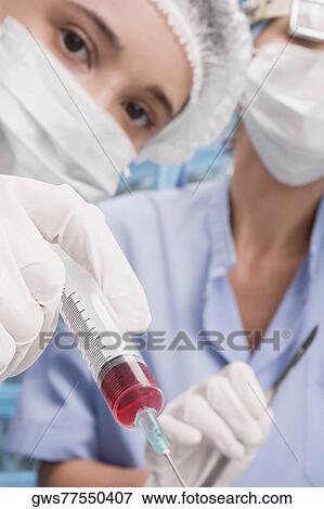 Portrait of a female surgeon holding a syringe View Large Photo Image Stock Photo - Portrait of a female surgeon holding a syringe. Fotosearch
