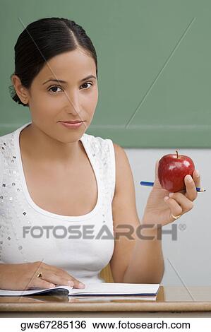 Portrait of a female teacher holding an apple and smirking View Large Photo Image Stock Photograph - Portrait of a female teacher holding an apple and smirking. Fotosearch