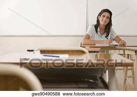 Portrait of a female teacher sitting in a classroom View Large Photo Image Stock Photo - Portrait of a female teacher sitting in a classroom. Fotosearch
