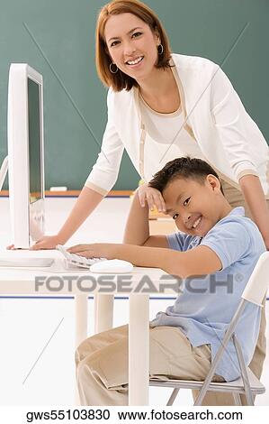 Stock Image - Portrait of a female teacher smiling with her student in a classroom. Fotosearch