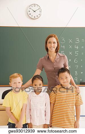 Portrait of a female teacher standing with her students in a classroom View Large Photo Image Stock Photo - Portrait of a female teacher standing with her students in a classroom. Fotosearch