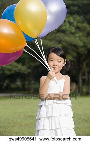 Portrait of a girl holding balloons in a park View Large Photo Image Stock Image - Portrait of a girl holding balloons in a park. Fotosearch