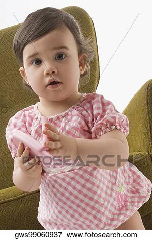 Portrait of a girl playing with a toy phone View Large Photo Image Stock Photo - Portrait of a girl playing with a toy phone. Fotosearch
