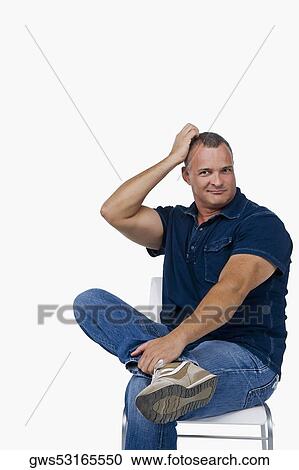 Stock Image - Portrait of a mature man sitting on a chair and scratching his head. Fotosearch