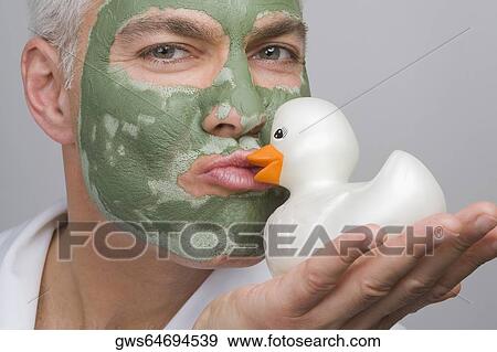 Portrait of a mature man wearing a facial mask and kissing a rubber duck View Large Photo Image Stock Photo - Portrait of a mature man wearing a facial mask and kissing a rubber duck. Fotosearch