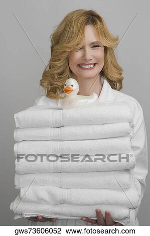 Portrait of a mature woman holding a stock of folded towels and smiling View Large Photo Image Stock Image - Portrait of a mature woman holding a stock of folded towels and smiling. Fotosearch