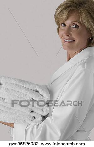Portrait of a mature woman holding a stack of folded towels and smiling View Large Photo Image Stock Image - Portrait of a mature woman holding a stack of folded towels and smiling. Fotosearch
