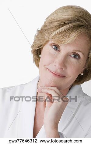 Stock Image - Portrait of a mature woman smiling with her hand on her chin. Fotosearch