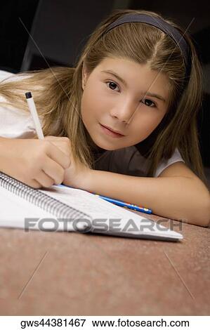 Portrait of a schoolgirl lying on the floor and writing on a textbook View Large Photo Image Stock Photo - Portrait of a schoolgirl lying on the floor and writing on a textbook. Fotosearch