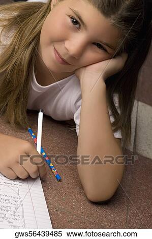 Portrait of a schoolgirl lying on the floor and writing on a textbook View Large Photo Image Stock Photography - Portrait of a schoolgirl lying on the floor and writing on a textbook. Fotosearch
