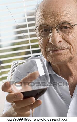 Stock Photograph - Portrait of a senior man holding a glass of wine. Fotosearch