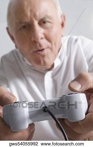 Portrait of a senior man playing a video game View Large Photo Image Stock Image - Portrait of a senior man playing a video game. Fotosearch