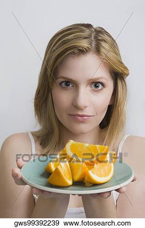 Stock Photo - Portrait of a teenage girl holding a plate of oranges. Fotosearch