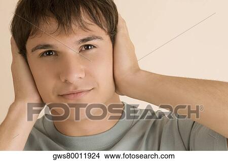 Picture - Portrait of a young man covering his ears with his hands. Fotosearch