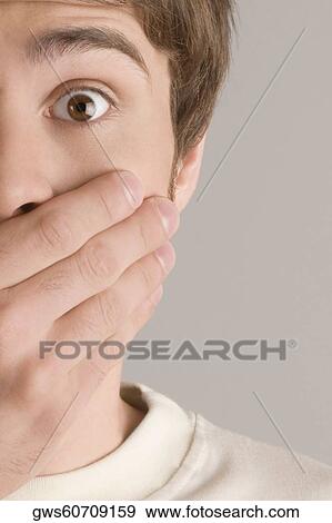 Portrait of a young man covering his mouth with his hand View Large Photo Image Stock Photo - Portrait of a young man covering his mouth with his hand. Fotosearch
