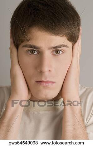 Portrait of a young man covering his ears with his hands View Large Photo Image Stock Photo - Portrait of a young man covering his ears with his hands. Fotosearch