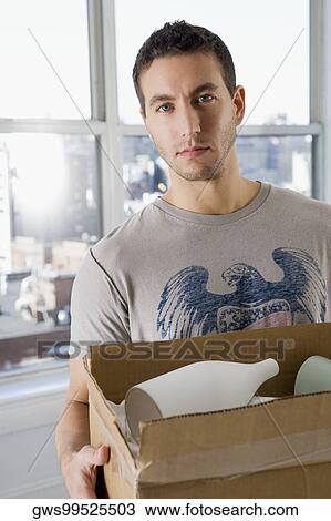Portrait of a young man holding a cardboard box View Large Photo Image Stock Image - Portrait of a young man holding a cardboard box. Fotosearch