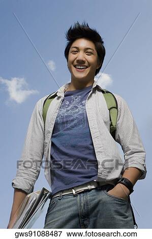 Portrait of a young man holding books and smiling View Large Photo Image Stock Photo - Portrait of a young man holding books and smiling. Fotosearch