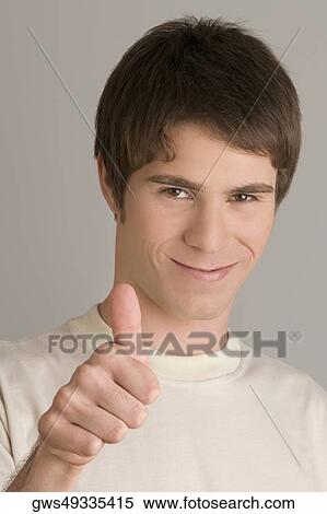 Portrait of a young man showing a thumbs up sign View Large Photo Image Stock Photography - Portrait of a young man showing a thumbs up sign. Fotosearch