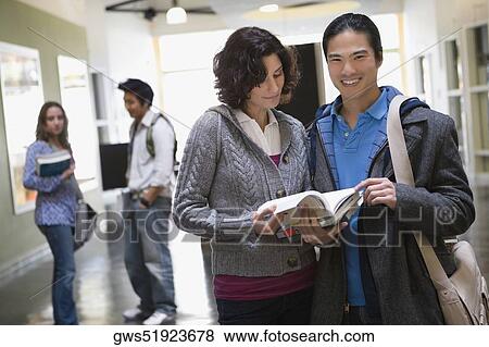 Portrait of a young man standing with a young woman holding books and smiling View Large Photo Image Stock Photo - Portrait of a young man standing with a young woman holding books and smiling. Fotosearch