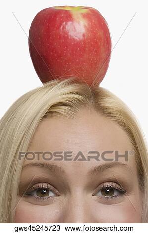 Portrait of a young woman balancing an apple on her head View Large Photo Image Stock Image - Portrait of a young woman balancing an apple on her head. Fotosearch