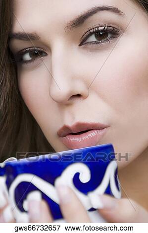 Portrait of a young woman blowing into a tea cup View Large Photo Image Stock Photo - Portrait of a young woman blowing into a tea cup. Fotosearch