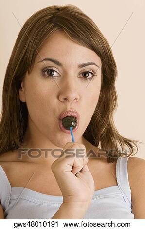 Portrait of a young woman eating a lollipop View Large Photo Image Stock Image - Portrait of a young woman eating a lollipop. Fotosearch