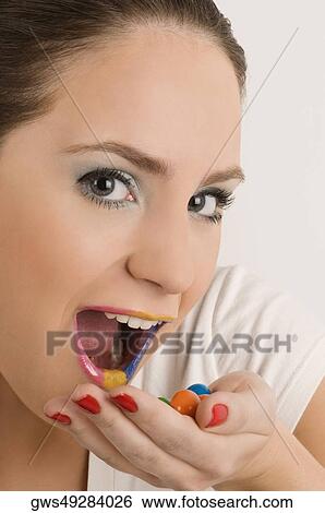 Stock Photograph - Portrait of a young woman eating candies. Fotosearch