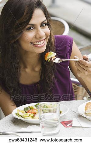 Portrait of a young woman eating salad at a sidewalk cafe View Large Photo Image Stock Photograph - Portrait of a young woman eating salad at a sidewalk cafe. Fotosearch