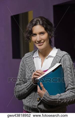Portrait of a young woman holding a book and smiling View Large Photo Image Stock Image - Portrait of a young woman holding a book and smiling. Fotosearch