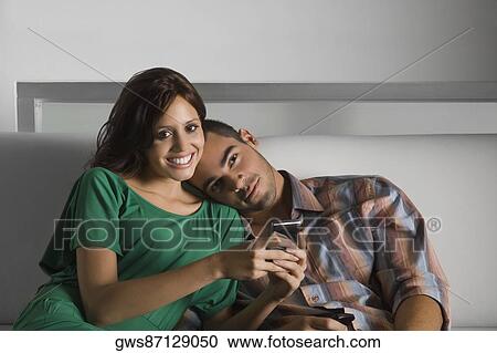 Portrait of a young woman holding a mobile phone and a young man leaning on her shoulder View Large Photo Image Stock Image - Portrait of a young woman holding a mobile phone and a young man leaning on her shoulder. Fotosearch